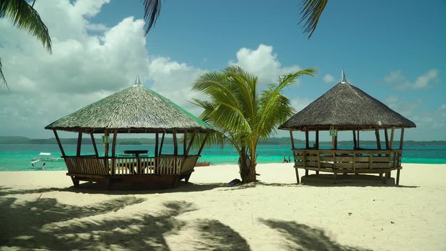 Bungalows and gazebos on a sandy beach with palm trees on a tropical island, Philippines. Summer and travel vacation concept
