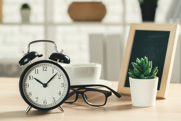 Classic vintage  alarm clock and  coffee cup on wooden background