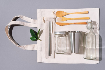 Fabric bags, glass jars, metal straws, bamboo cutlery on grey background with copy space. Eco...