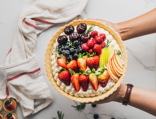 Hand holding Cake pie with strawberries blueberry on table food concept top view 