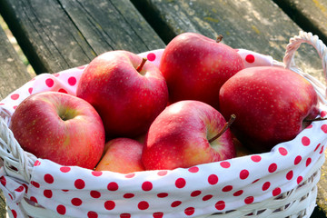 white basket with dotted textile full of red apples