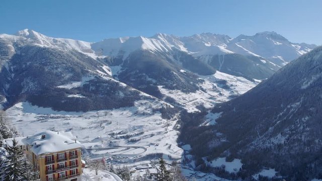 4K cinematic winter aerial shot in the swiss Alps, Switzerland. Camera flying over a hotel and discovering the scenic panorama