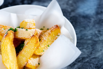 Close up view on French fries with sauce, garlic and cheese in craft paper. Fast food, snack. Tasty food photography for menu or banner. Selective, soft focus.