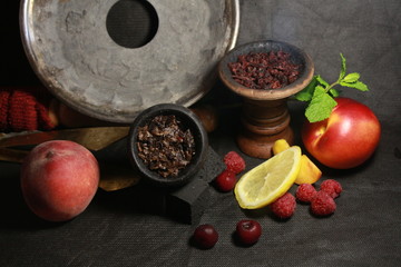 bowl with tobacco for hookah. fruits on a black background. smoke hookah