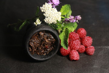 bowl with tobacco for hookah. berries on a black background
