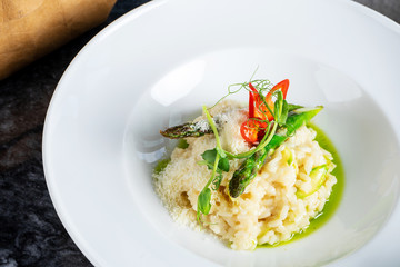 Close up view on tradtional and tasty risotto with parmesan, asparagus and chili. Mediterranean and italian cuisine. Soft, selective focus. Rise with asparagus. Copy space. Food photography