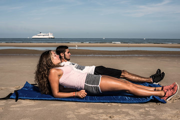 young couple doing pilate on the sunny beach