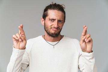 Worried young man standing isolated over gray background