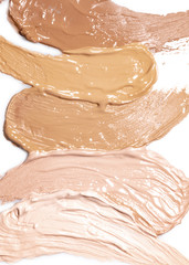 Deckende cremige Kosmetik, Foundation in hellem Braun, Beige mit gelbem Unterton, dunklem Beige, hellem Beige mit rosa Unterton, hellem Beige auf weissem Hintergrund