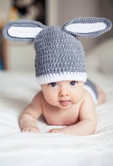 3 months baby in a knitted bunny suit lies on her stomach. Child. Cozy.