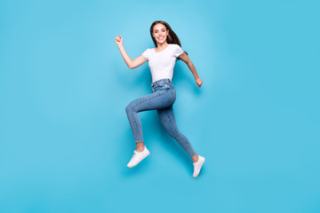 Fototapeta na wymiar Full length photo of cheerful youth running wearing white t-shirt denim jeans sneakers isolated over blue background