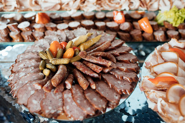 Cold cuts. Meat delicatessen plate. A variety of processed cold meat products Assorted meat products including ham and sausages. Thin slices of ham on cutting.