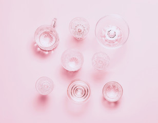 Many empty glasses on pink background. Top view, flat lay.