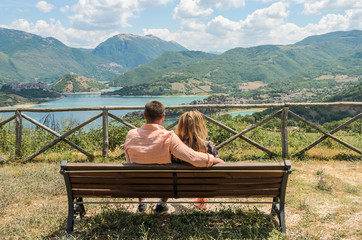 Loving couple sitting on a bench against the backdrop of a mountain lake Lago del Turano - happy family