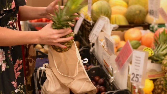 Woman in a supermarket takes fresh fruits to cotton bag. No plastic alternative. zero waste