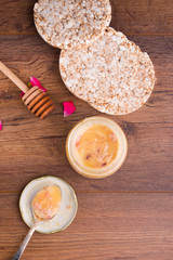 Honeycomb with wooden dipper and fresh blossom, jar with honey and plate with vintage spoons on dark rustic background.