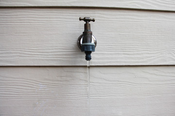 faucet on white wall with flowing water
