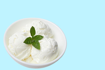 white bowl with white ice cream and green leaf isolated on a blue background. Place for your text or content. Copy space