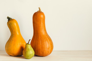 Two ripe organic  pumpkin and pear on a pastel beige background. Minimal eco concept for Thanksgiving card or background. Place for text.