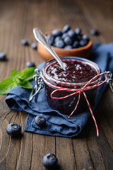 Healthy blueberry jam in a glass jar served with fresh berries