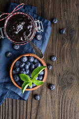 Healthy blueberry jam in a glass jar served with fresh berries with copy space
