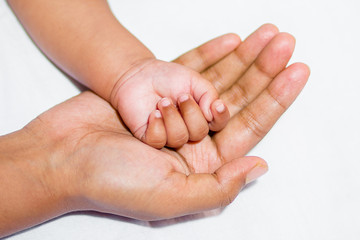 A new born baby's soft hand on mother's hand on a white background.