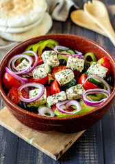Greek salad on a wooden background. Tomatoes, peppers, olives, cheese, onions. Healthy eating. Diet. Vegetarian food.