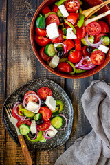 Greek salad on a wooden background. Tomatoes, peppers, olives, cheese, onions. Healthy eating. Diet. Vegetarian food.
