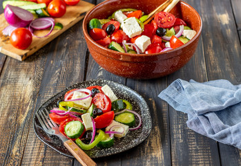 Greek salad on a wooden background. Tomatoes, peppers, olives, cheese, onions. Healthy eating. Diet. Vegetarian food.