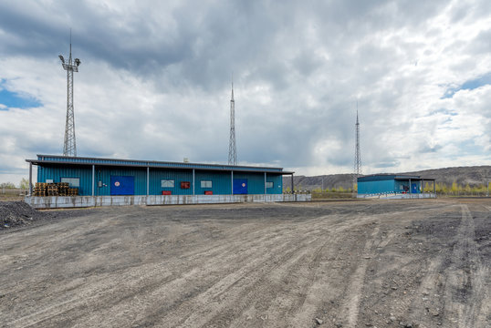 The territory of a small industrial warehouse. The warehouse is surrounded by lightning protection masts.