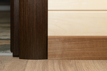 Adjacent laminate flooring, plinth and platbands made of wood