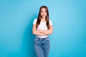 Portrait of pretty youngster with crossed arms looking wearing white t-shirt denim jeans isolated over blue background