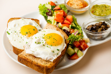 Fried eggs on toasted bread and salad