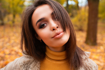 Fototapeta premium Outdoor atmospheric lifestyle photo of young beautiful lady. Brown hair and eyes. Warm autumn. Warm spring.Autumn woman in autumn park. Warm sunny weather. Fall concept.