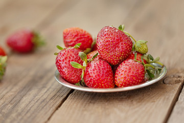Strawberries on a silver plate on wooden table