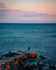 Naklejka premium Lonely fisherman on pier in susnet