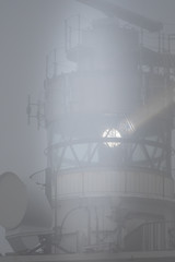 A lighthouse lights up on a foggy day