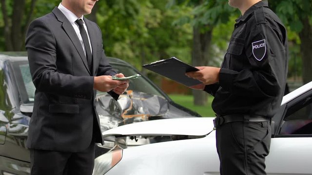 Policeman refusing to take bribe money from driver at car accident scene, law