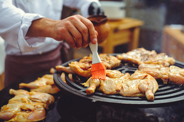 The chef is cooking meat on the grill. Golden grilled ribs and chicken steaks, delicious food