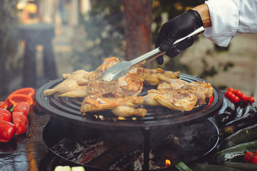 The chef is cooking meat on the grill. Golden rib steaks and chicken with grilled vegetables, delicious food
