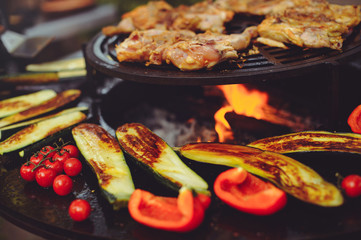The chef is cooking meat on the grill. Golden rib steaks and chicken with grilled vegetables, delicious food