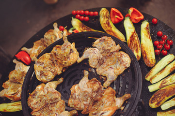 The chef is cooking meat on the grill. Golden rib steaks and chicken with grilled vegetables, delicious food