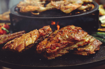 The chef is cooking meat on the grill. Golden rib steaks and chicken with grilled vegetables, delicious food