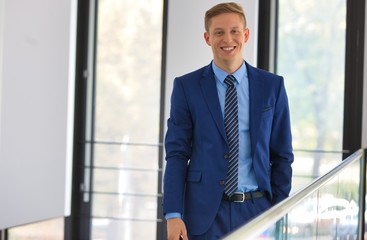 Fototapeta premium Portrait of smiling young businessman standing against window at office