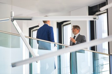 Low angle view of business colleagues discussing by railing at office