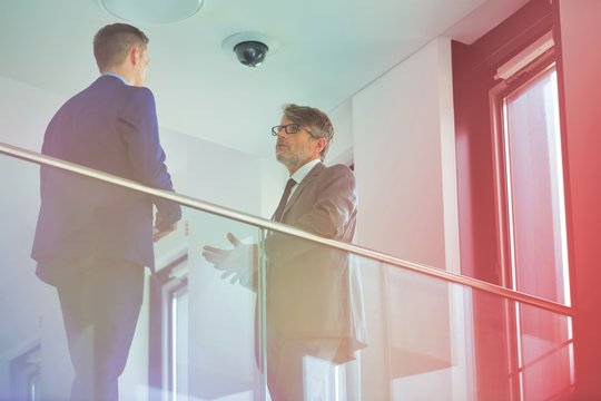 Low angle view of business colleagues discussing by railing at office