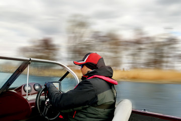 A man driving a boat at high speed rushes along the river. Smeared from speed terrain. Soft focus.