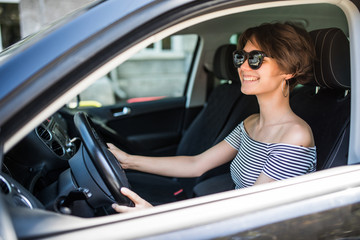Obraz na płótnie Canvas Smiling beautiful woman driving a car in the street
