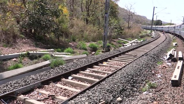 Moving train pov, man walking on a parallel track in India