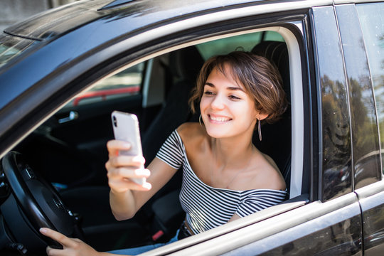 Young woman using cellphone to take photo inside a car